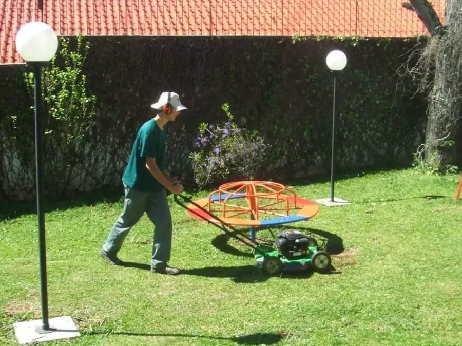 Jardineiro cortando a grama com cortador motorizado em quintal residencial