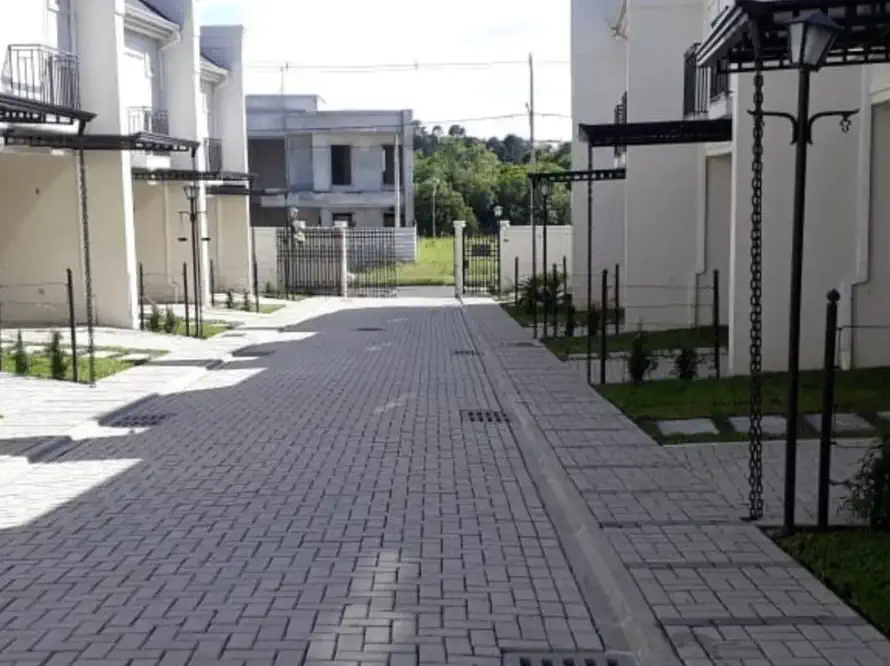 Rua interna de condomínio com calçamento limpo, gramado e arbustos sob manutenção programada